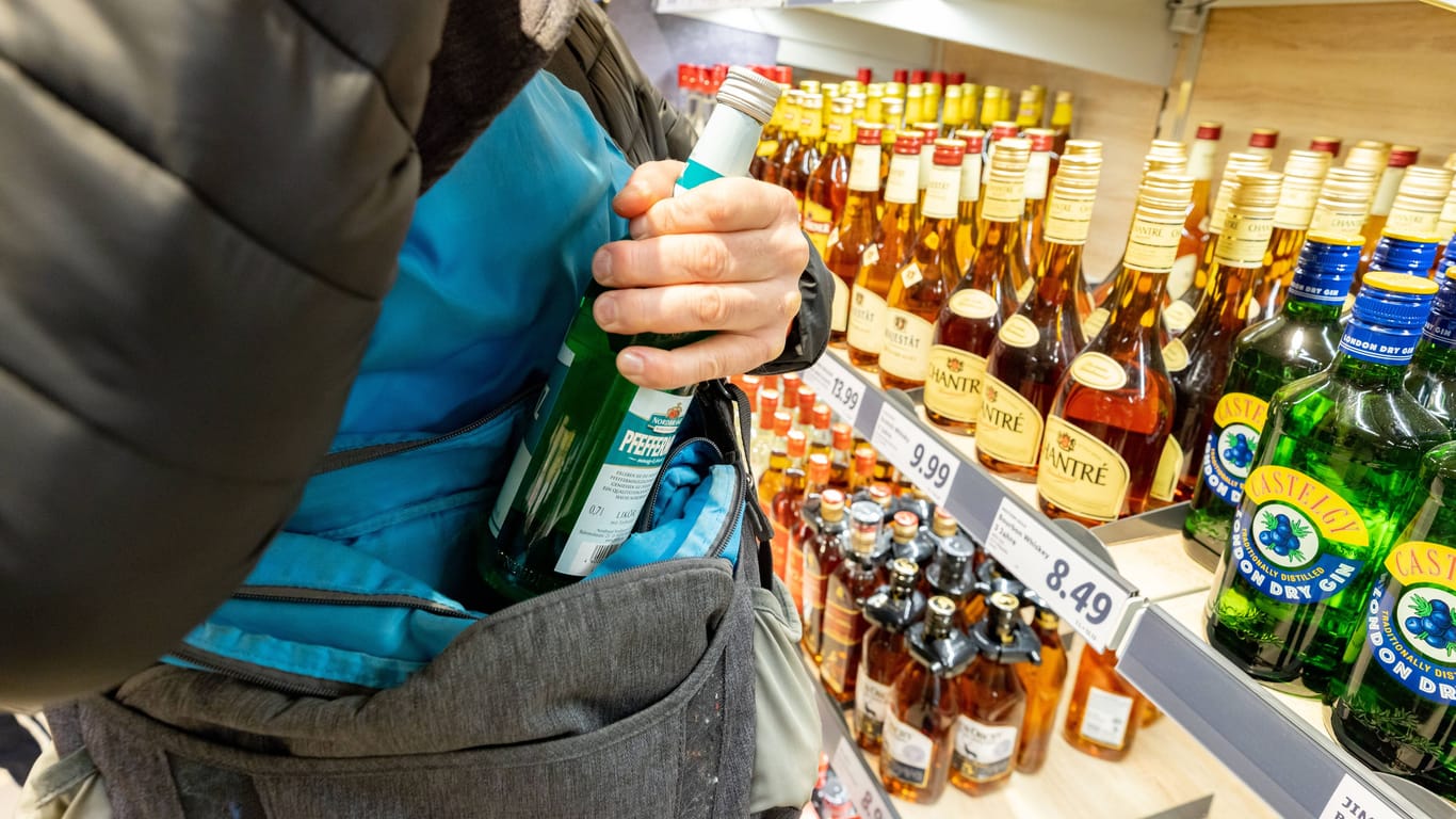 Die Hände eines Ladendiebes beim Diebstahl von einer Flasche Pfefferminzlikör fotografiert (Archivbild): Alkohl ist beliebtes Diebesgut, aber auch Sonnenbrillen oder Modeschmuck.