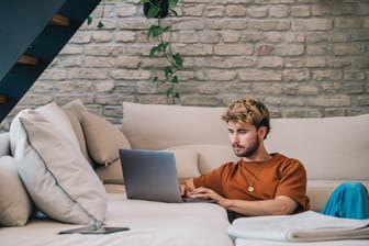 Ein junger Mann arbeitet am Laptop