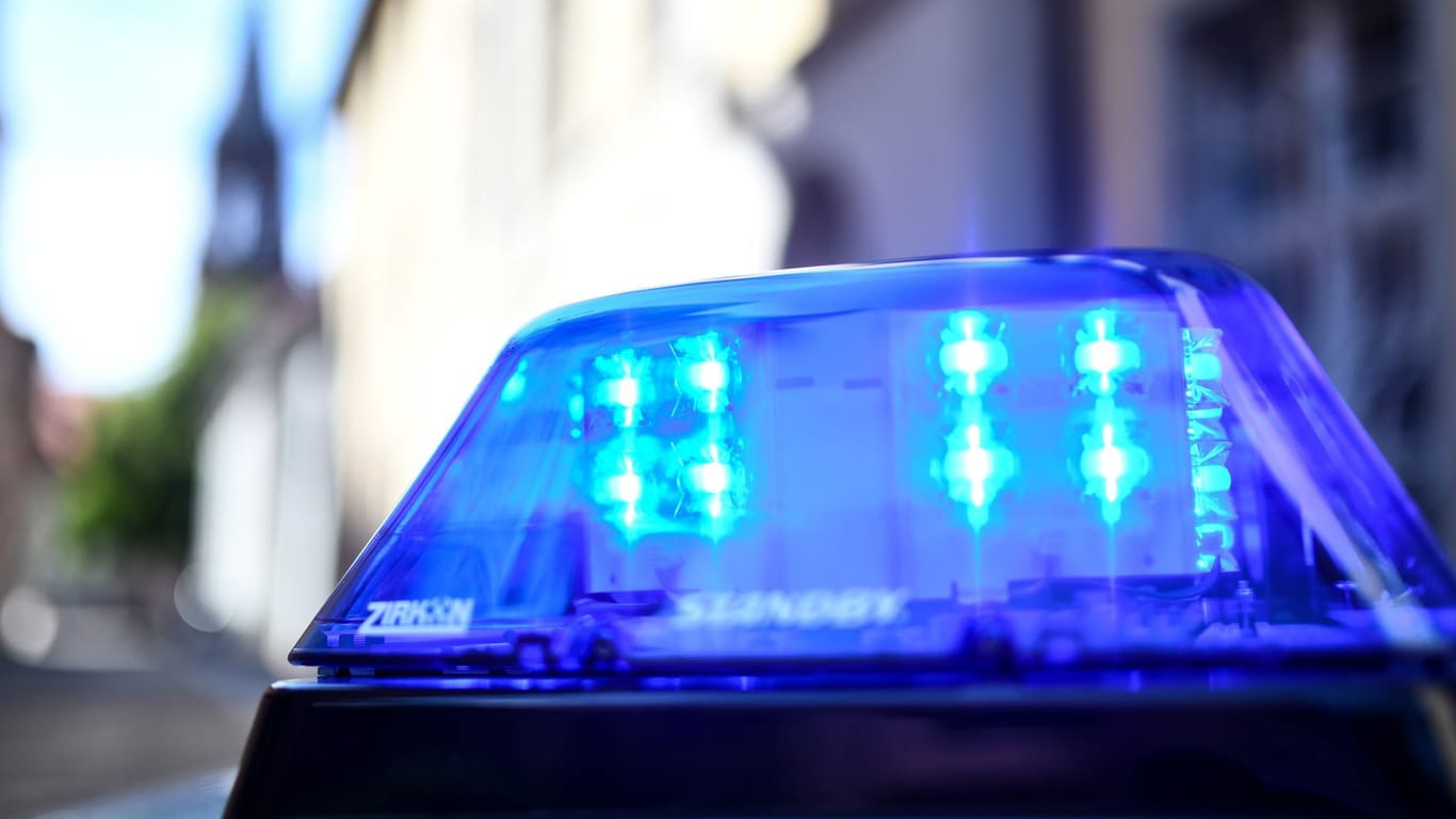 Ein Polizeiauto mit blinkendem Blaulicht steht vor einem Gebäude