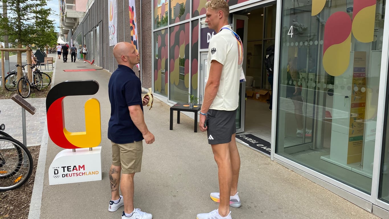 Fabian Hambüchen ist im Olympischen Dorf immer noch bekannt und beliebt. Hier spricht er vor dem Eingang des deutschen Quartiers mit Ruderer Oliver Zeidler.