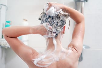 Rückansicht einer Frau, die sich die Haare wäscht.