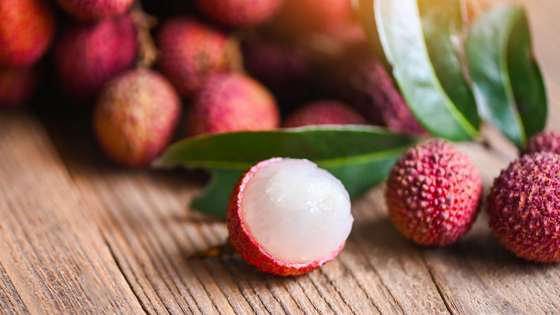 Lychee fruit and green leaf on wooden background, fresh ripe lychee peeled from lychee tree at tropical fruit Thailand in summer