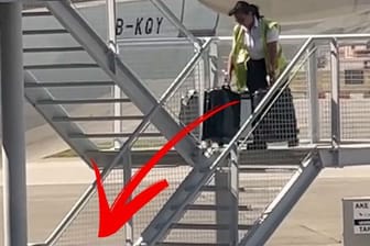 Eine Flughafenmitarbeiterin feuert Koffer eine Treppe hinunter.