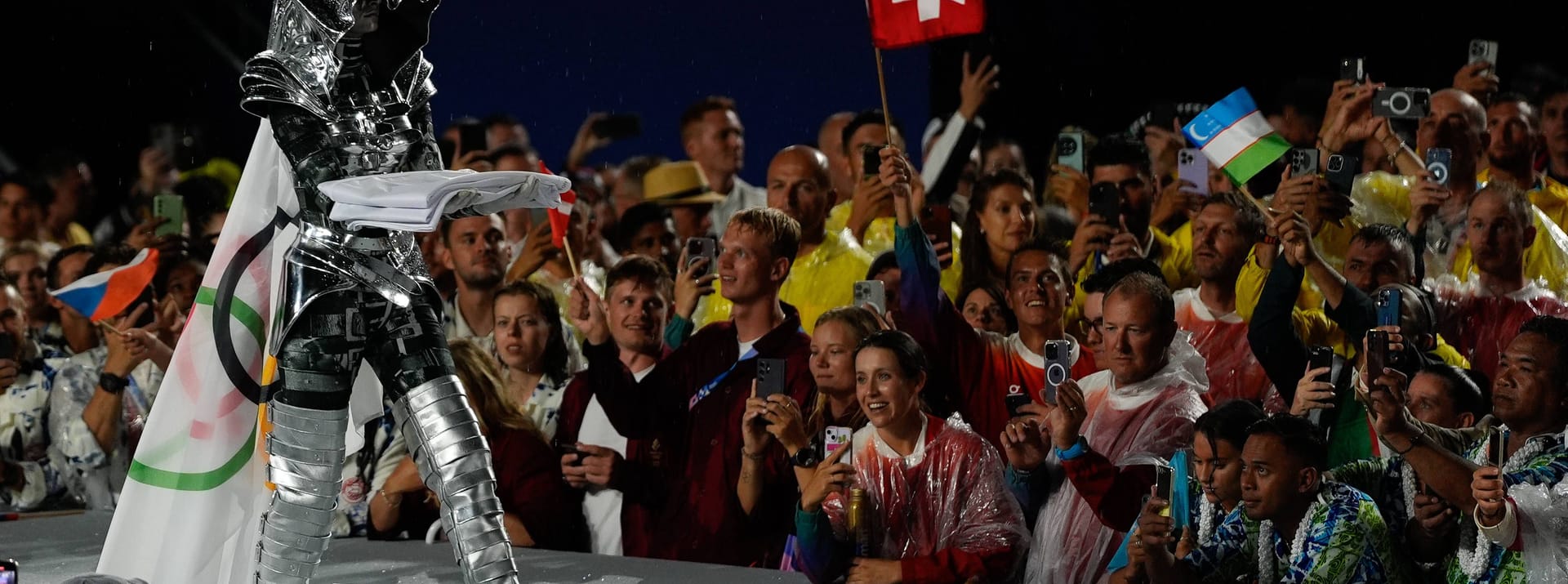 Die Reiterin schritt dann mit dem Eiffelturm im Rücken in Richtung des Fahnenmastes und hisste die olympische Fahne. Das Ganze wurde untermalt von einem Orchester, das die olympische Hymne spielte.