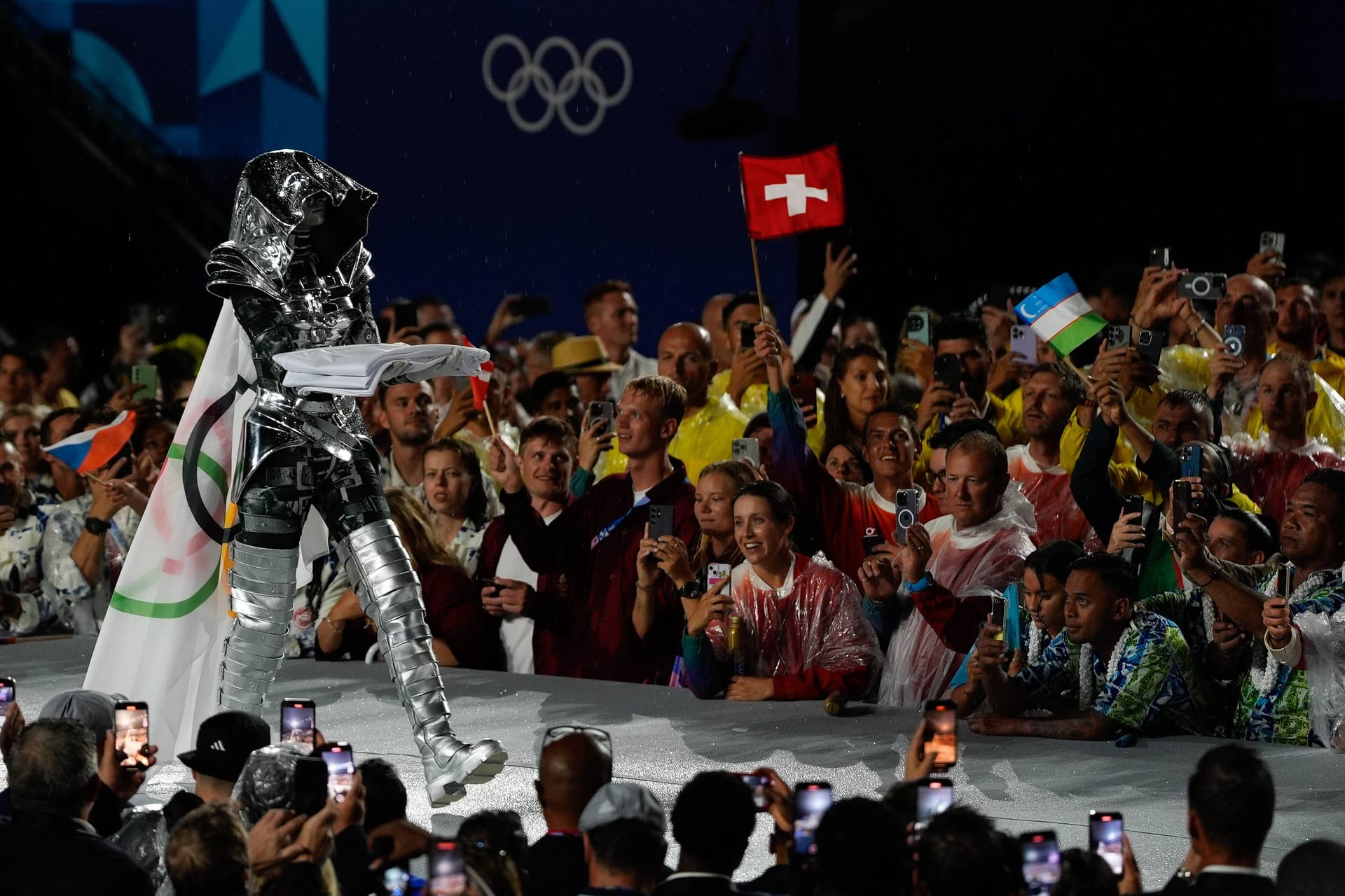 Die Reiterin schritt dann mit dem Eiffelturm im Rücken in Richtung des Fahnenmastes und hisste die olympische Fahne. Das Ganze wurde untermalt von einem Orchester, das die olympische Hymne spielte.