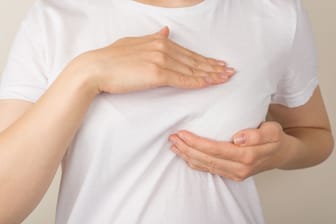Eine Frau tastet ihre linke Brust ab