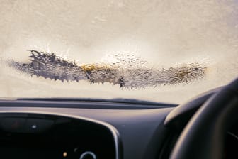 Frosted car windshield with patches of defrosted area. Winter cold season concept. Getting ready to travel