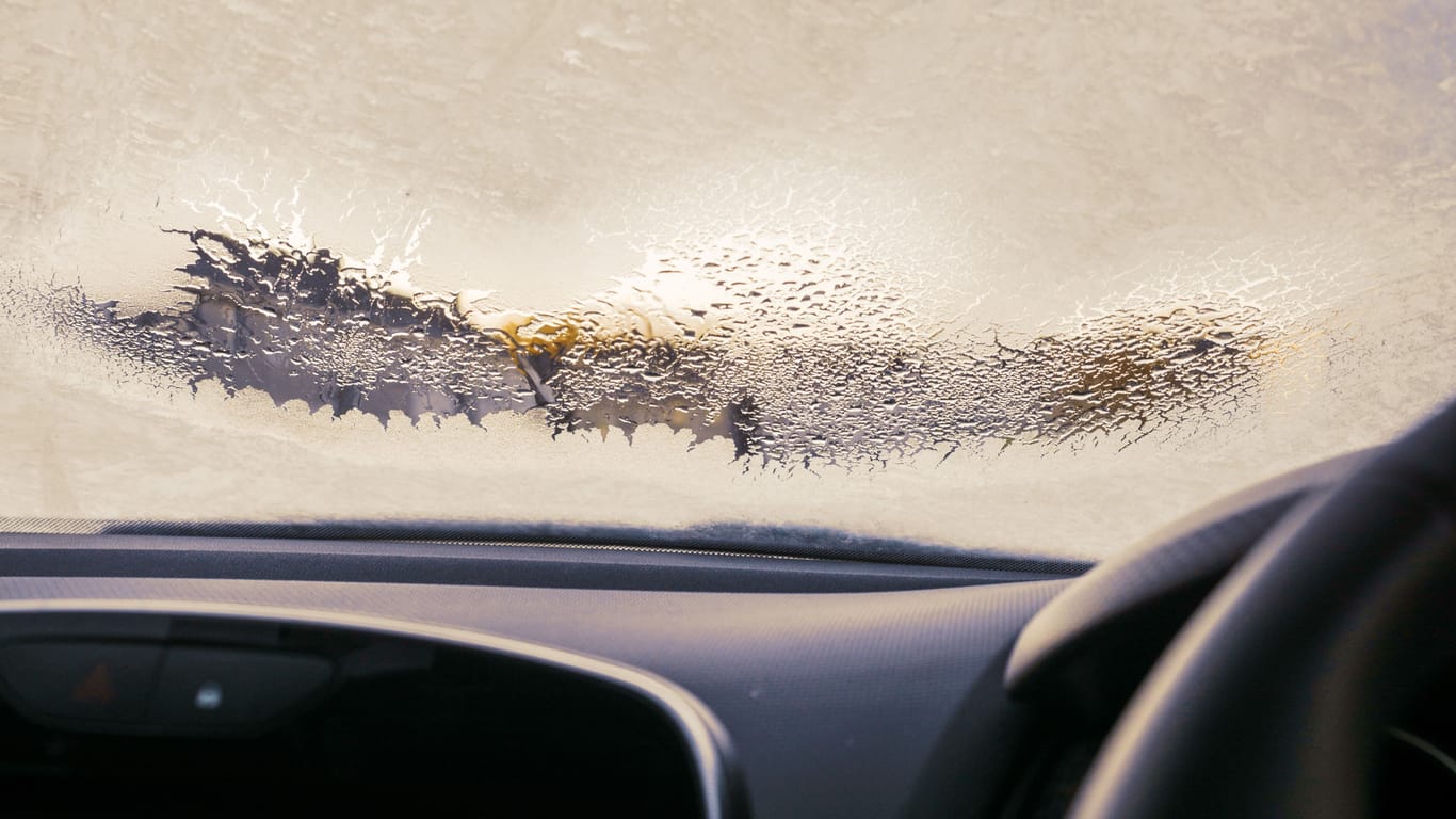 Frosted car windshield with patches of defrosted area. Winter cold season concept. Getting ready to travel