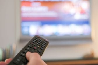 Eine Hand bedient eine Fernbedienung für ein TV-Gerät: Verträge über TV-Kosten haben zu Abmahnungen geführt.