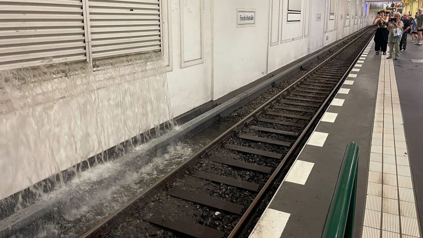 10.07.2024, Berlin: Wasser strömt durch eine Lüftungsöffnung ins Gleisbett im U-Bahnhof Friedrichstraße. Ein schweres Gewitter mit heftigem Regen ist über Berlin gezogen und hat den sommerlichen Wochenauftakt vorerst unterbrochen.