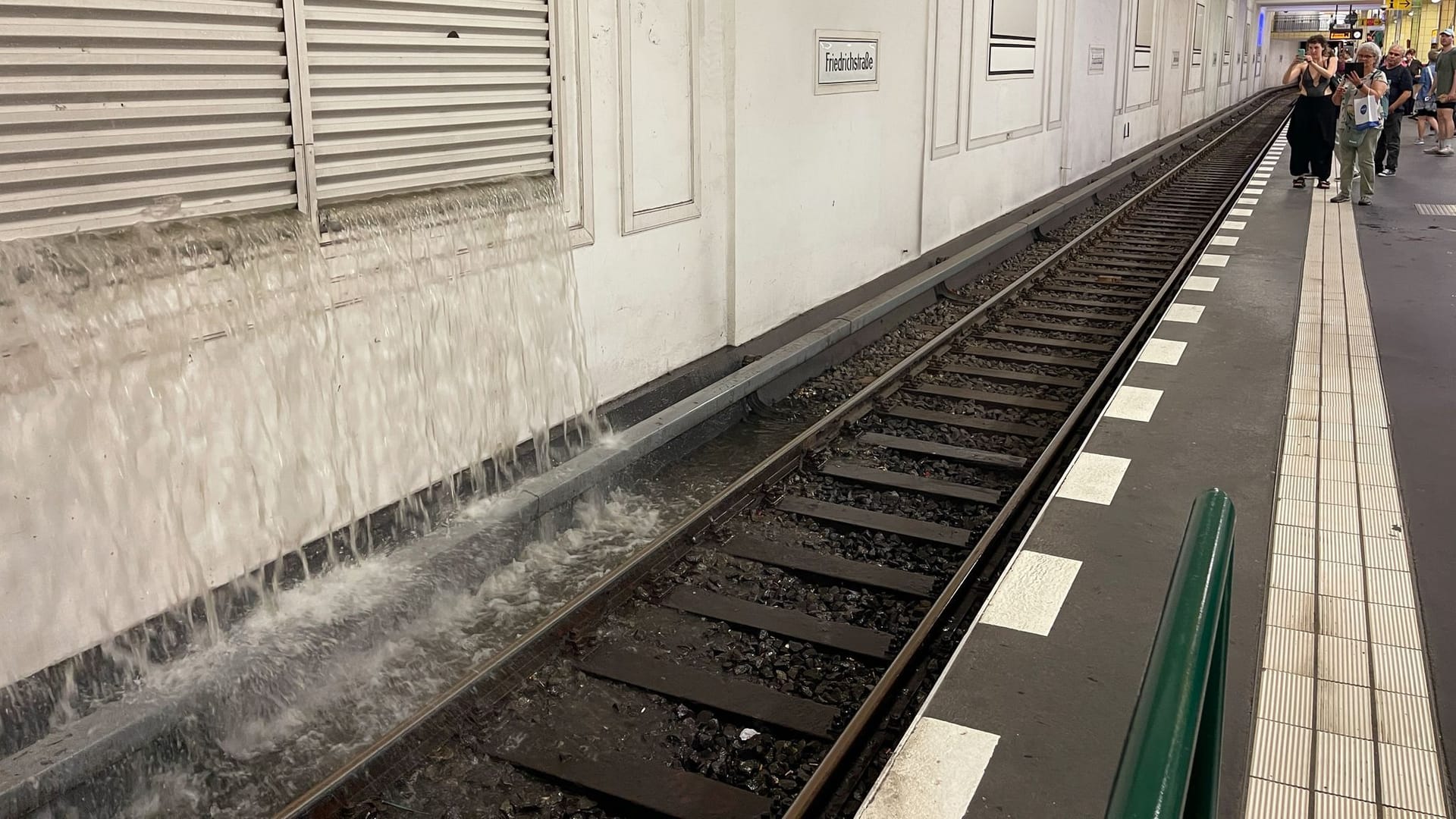 10.07.2024, Berlin: Wasser strömt durch eine Lüftungsöffnung ins Gleisbett im U-Bahnhof Friedrichstraße. Ein schweres Gewitter mit heftigem Regen ist über Berlin gezogen und hat den sommerlichen Wochenauftakt vorerst unterbrochen.