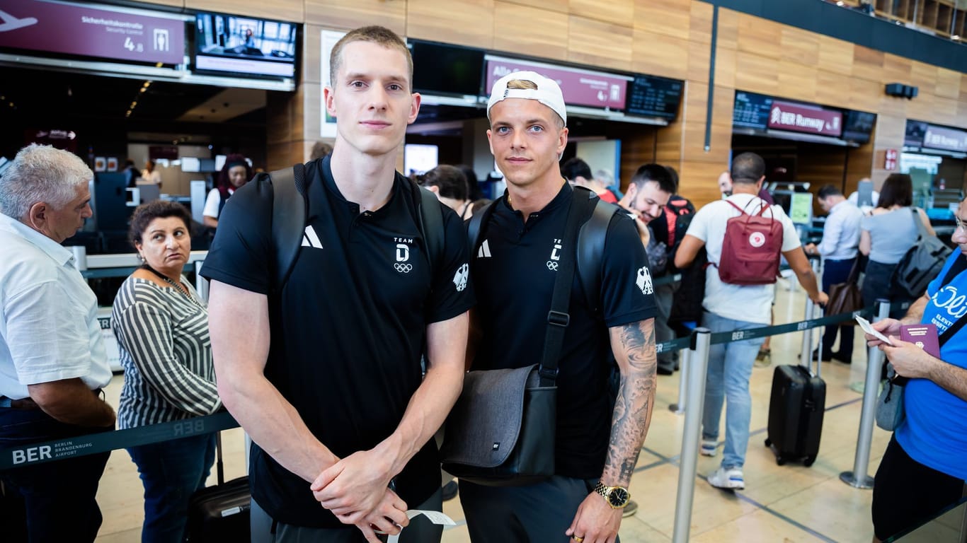 Lars Rüdiger (l), Timo Barthel, beide deutsche Olympiasportler im Wasserspringen, warten am Hauptstadtflughafen BER vor der Sicherheitskontrolle.