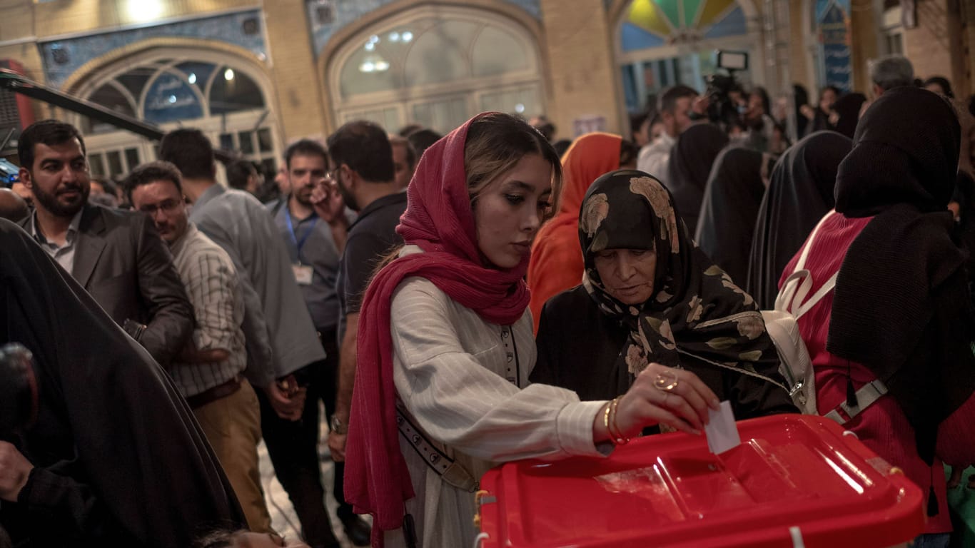 Iranische Frauen an einer Wahlurne.