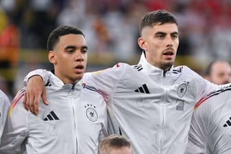 Jamal Musiala, Kai Havertz und Robert Andrich (v.l.n.r.) bei der Nationalhymne: Ein Detail macht die Jacken der DFB-Stars besonders.