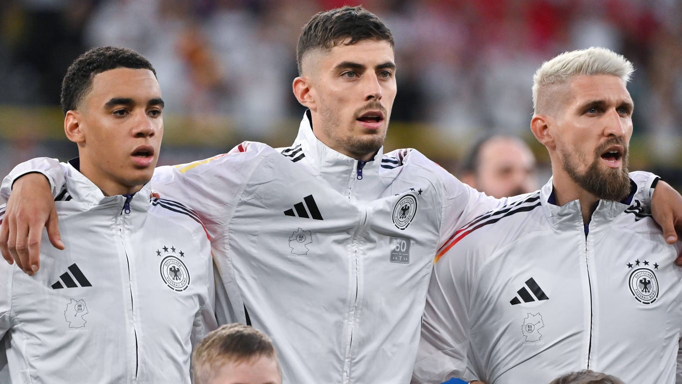 Jamal Musiala, Kai Havertz und Robert Andrich (v.l.n.r.) bei der Nationalhymne: Ein Detail macht die Jacken der DFB-Stars besonders.