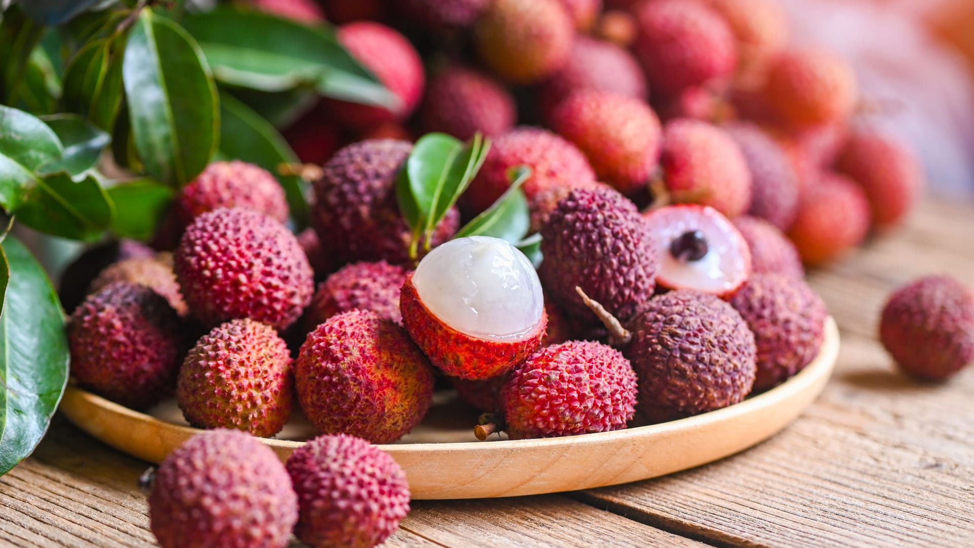 Lychee frui with green leaf on wooden plate background , fresh ripe lychee peeled from lychee tree at tropical fruit Thailand in summer