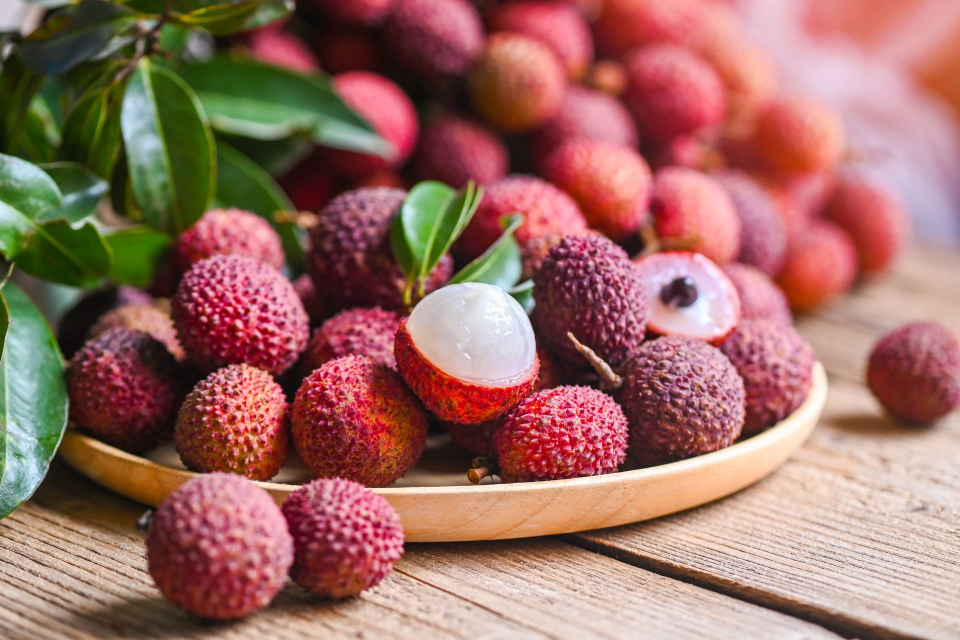 Lychee frui with green leaf on wooden plate background , fresh ripe lychee peeled from lychee tree at tropical fruit Thailand in summer