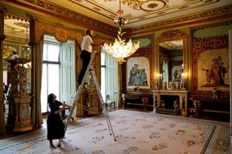 Letzte Vorbereitungen werden im Centre Room getroffen, wo sich Mitarbeiter des Royal Collection Trust um einen Kronleuchter im Ostflügel des Buckingham Palace, London, kümmern.