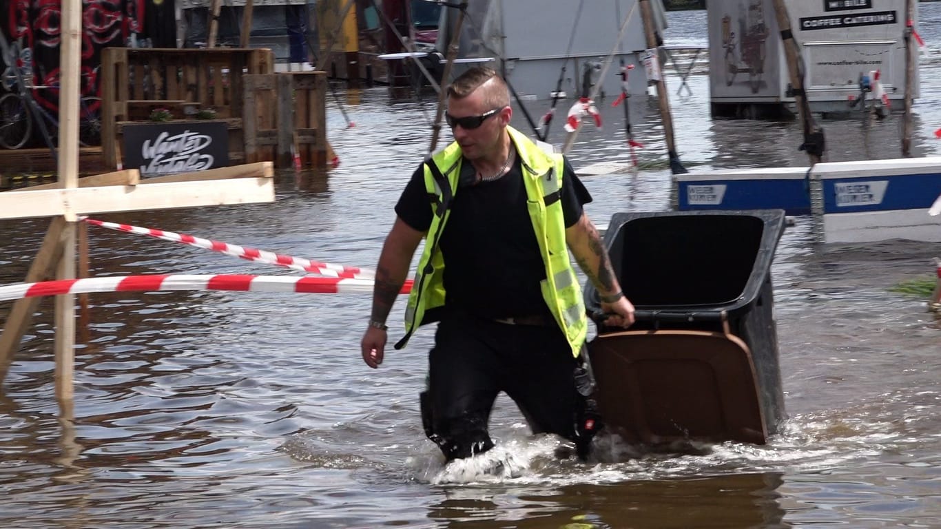 Ein Mitarbeiter zieht eine Mülltonne aus den Fluten: Am Donnerstag ist das Gelände des "Breminale"-Festival überflutet worden.