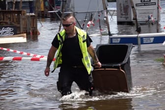 Ein Mitarbeiter zieht eine Mülltonne aus den Fluten: Am Donnerstag ist das Gelände des "Breminale"-Festival überflutet worden.
