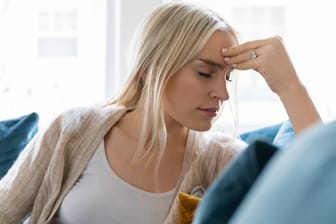 Eine junge Frau klagt über Kopfschmerzen (Symbolbild): Viele Menschen halten sich gerade im Sommer für "wetterfühlig".