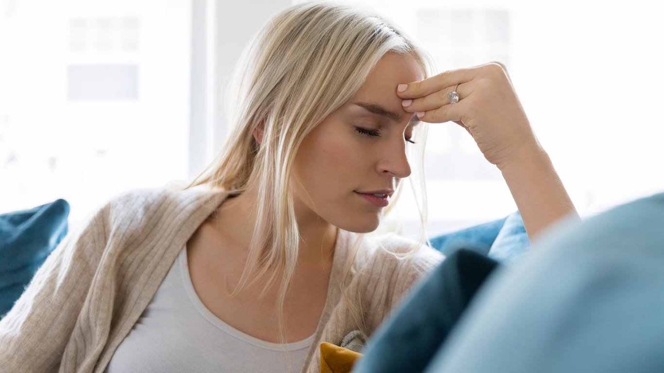 Eine junge Frau klagt über Kopfschmerzen (Symbolbild): Viele Menschen halten sich gerade im Sommer für "wetterfühlig".