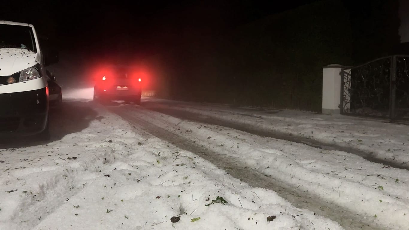 Ein Auto fährt wie durch eine Winterlandschaft mitten im Sommer. Ein Gewitter sorgte für eine Decke aus Hagelkörnern.