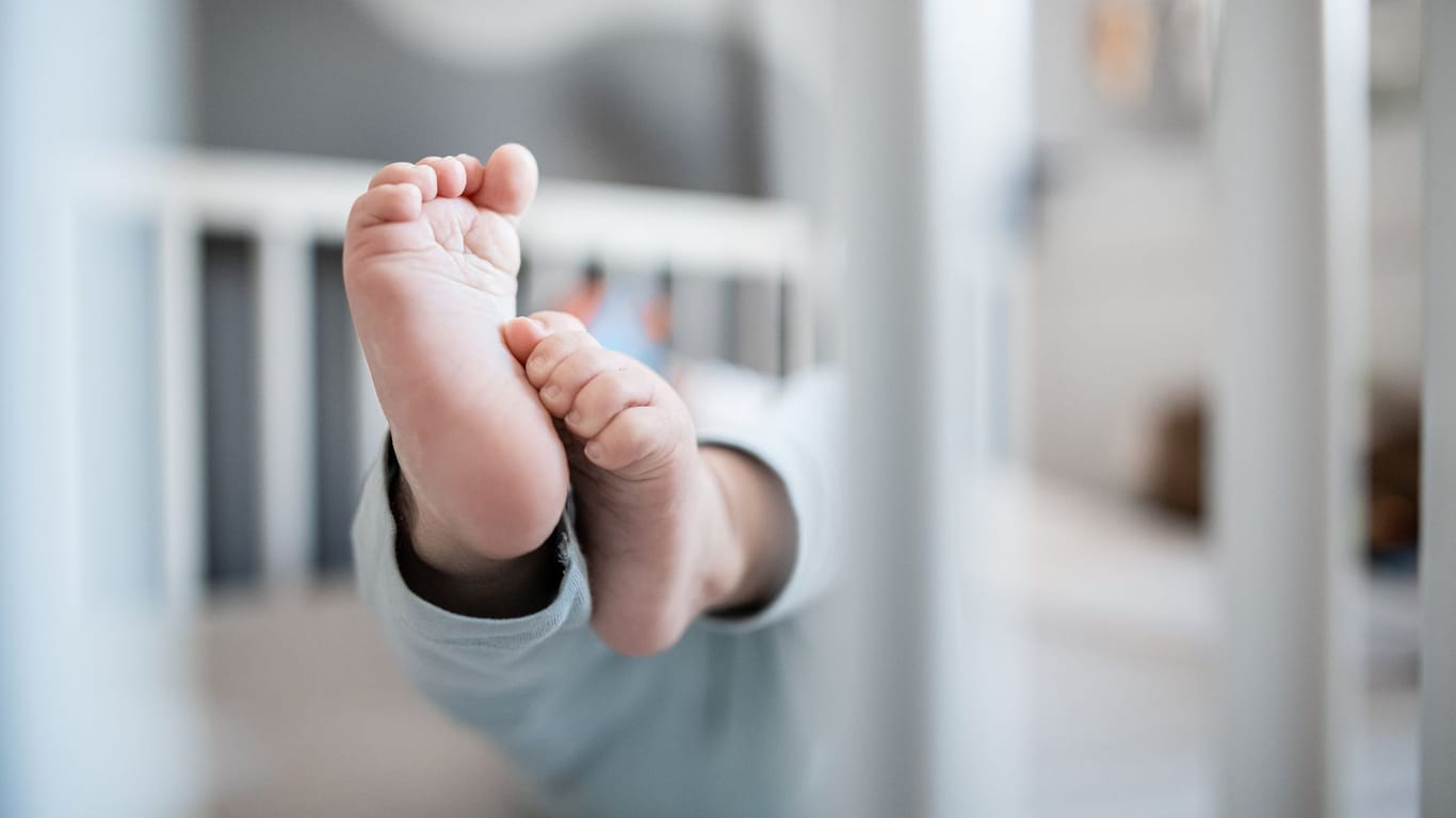 Ein Baby liegt in einem Beistellbett