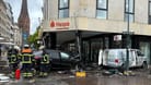 Helfer stehen an einem demolierten Auto vor der Hamburger Sparkasse (Haspa) am Jungfernstieg. Ein Auto ist in Hamburg in eine Sparkasse gefahren, es gab mehrere Verletzte.