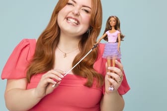 Lucy Edwards, einer blinden Rundfunksprecherin und Behindertenaktivistin, die mit der ersten blinden Barbie posiert.