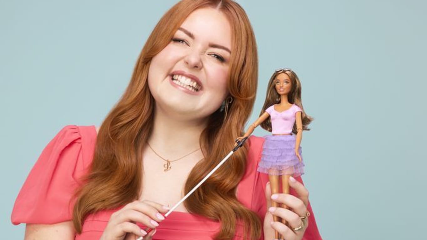 Lucy Edwards, einer blinden Rundfunksprecherin und Behindertenaktivistin, die mit der ersten blinden Barbie posiert.