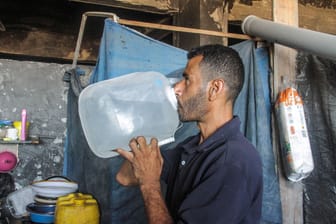 Ein Familienvater trinkt aufbereitetes Wasser im nördlichen Gazastreifen.