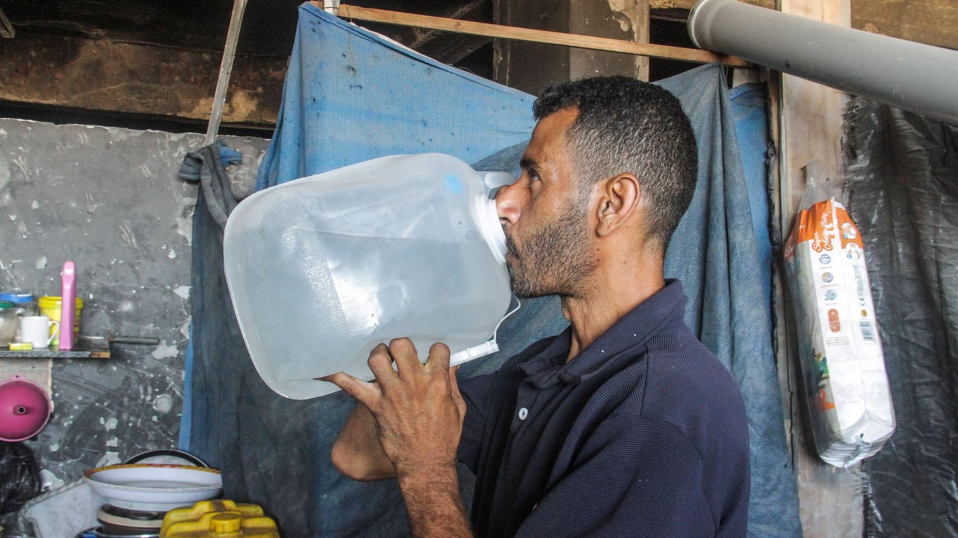 Ein Familienvater trinkt aufbereitetes Wasser im nördlichen Gazastreifen.