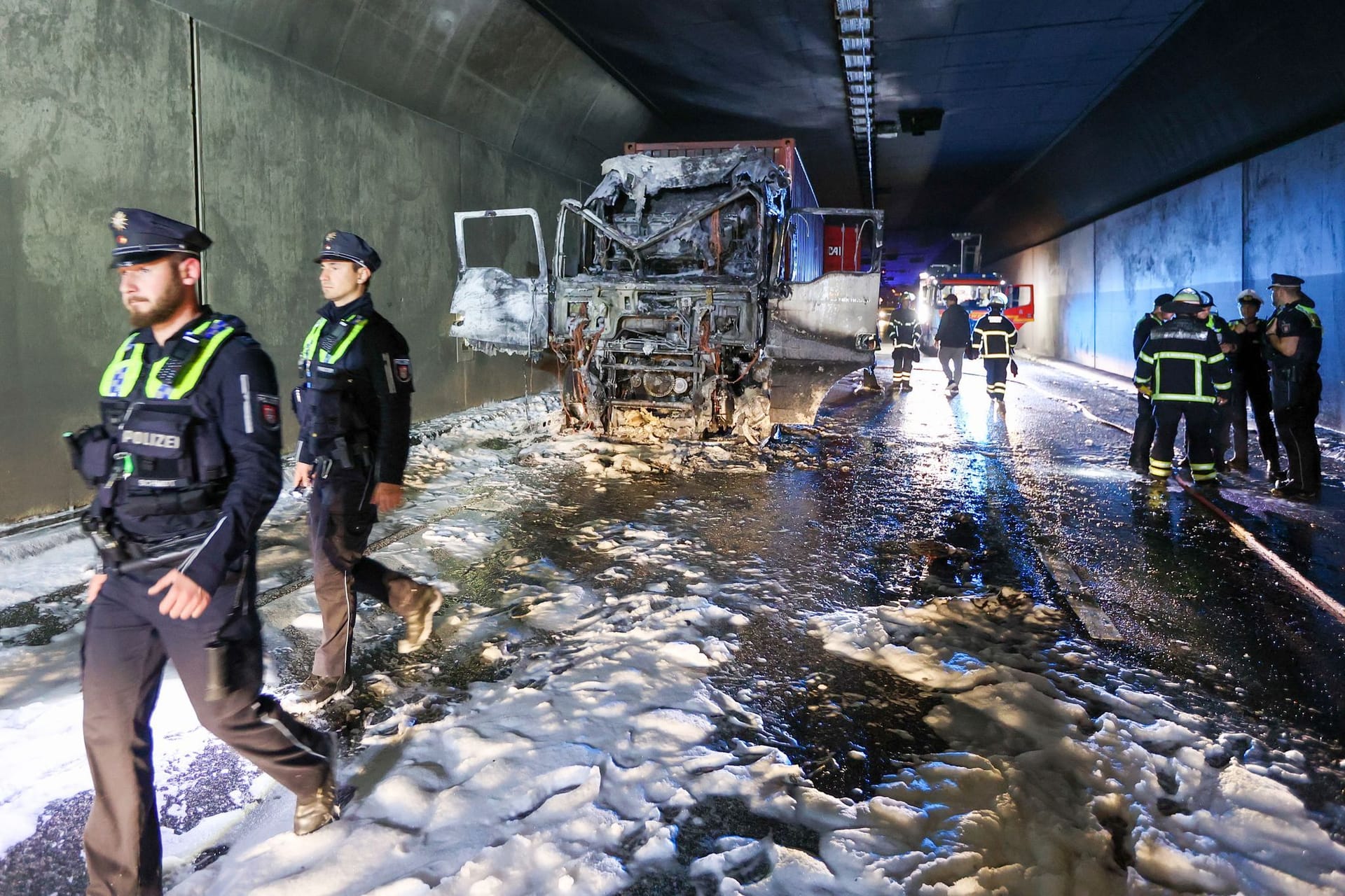 Einsatzkräfte stehen im Elbtunnel an einer ausgebrannten Lkw-Zugmaschine. Wegen des Brandes in der Röhre in Fahrtrichtung Norden war die Verkehrsachse zeitweise gesperrt.