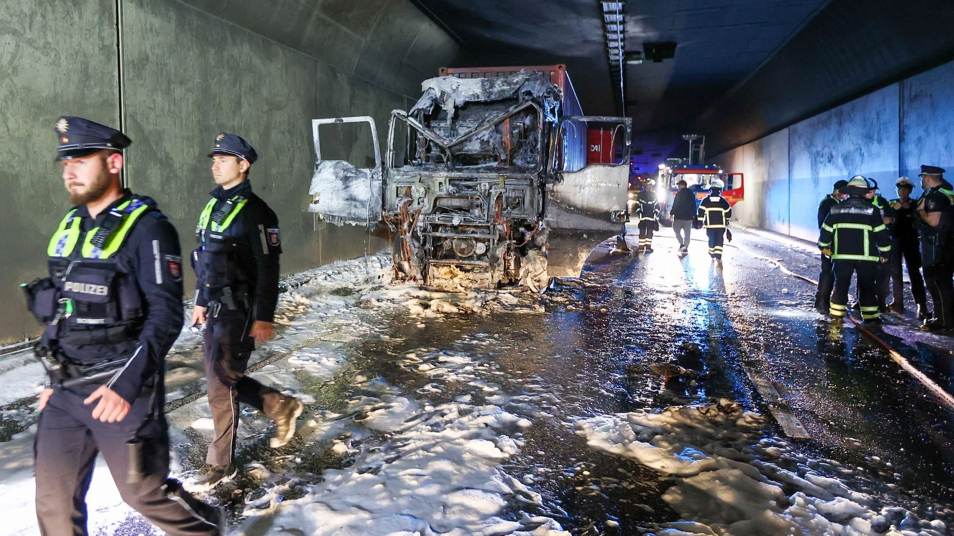 Einsatzkräfte stehen im Elbtunnel an einer ausgebrannten Lkw-Zugmaschine. Wegen des Brandes in der Röhre in Fahrtrichtung Norden war die Verkehrsachse zeitweise gesperrt.