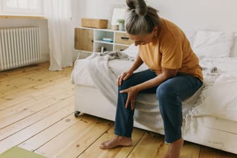 Frau mit Beinschmerzen: Krampfadern können sich auf unterschiedliche Weise bemerkbar machen.