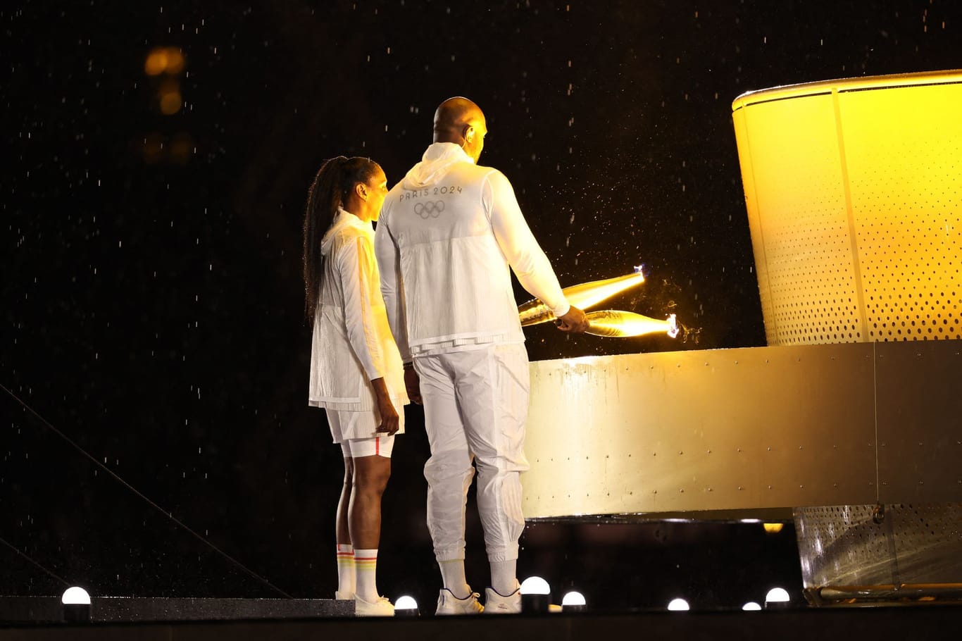 Teddy Riner und Marie-Jose Perec zünden das olympische Feuer an.