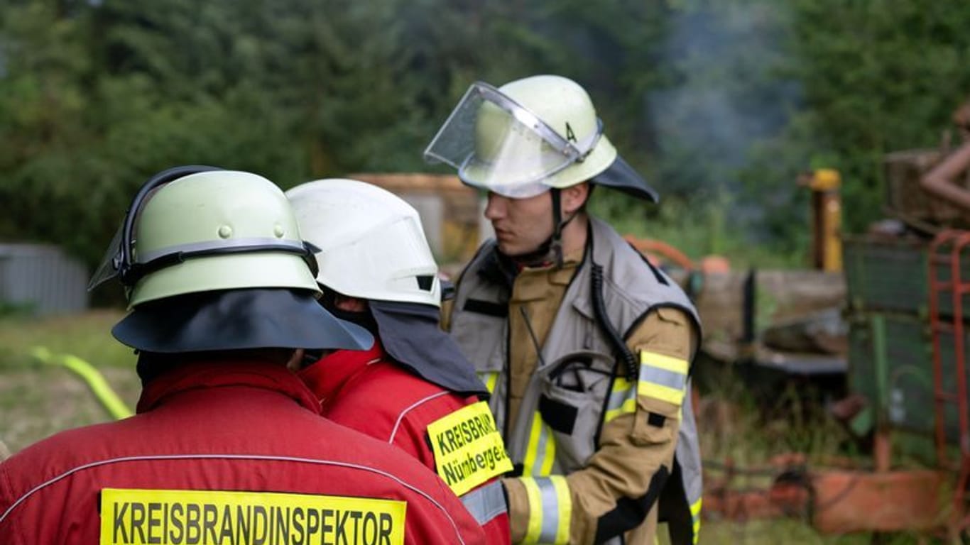 Einsatzkräfte der Feuerwehr stehen auf dem Gartengrundstück: Nach stundenlanger Fahndung nach einem Bewaffneten in Altdorf bei Nürnberg hat die Polizei die Leiche eines Mannes gefunden.