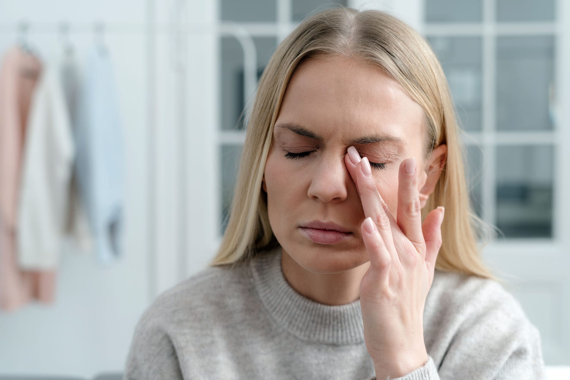 Eine Frau fasst sich ans Auge: Wer psychisch belastet ist und immer wieder tränende Augen hat, fragt sich möglicherweise, ob ein Zusammenhang bestehen kann.