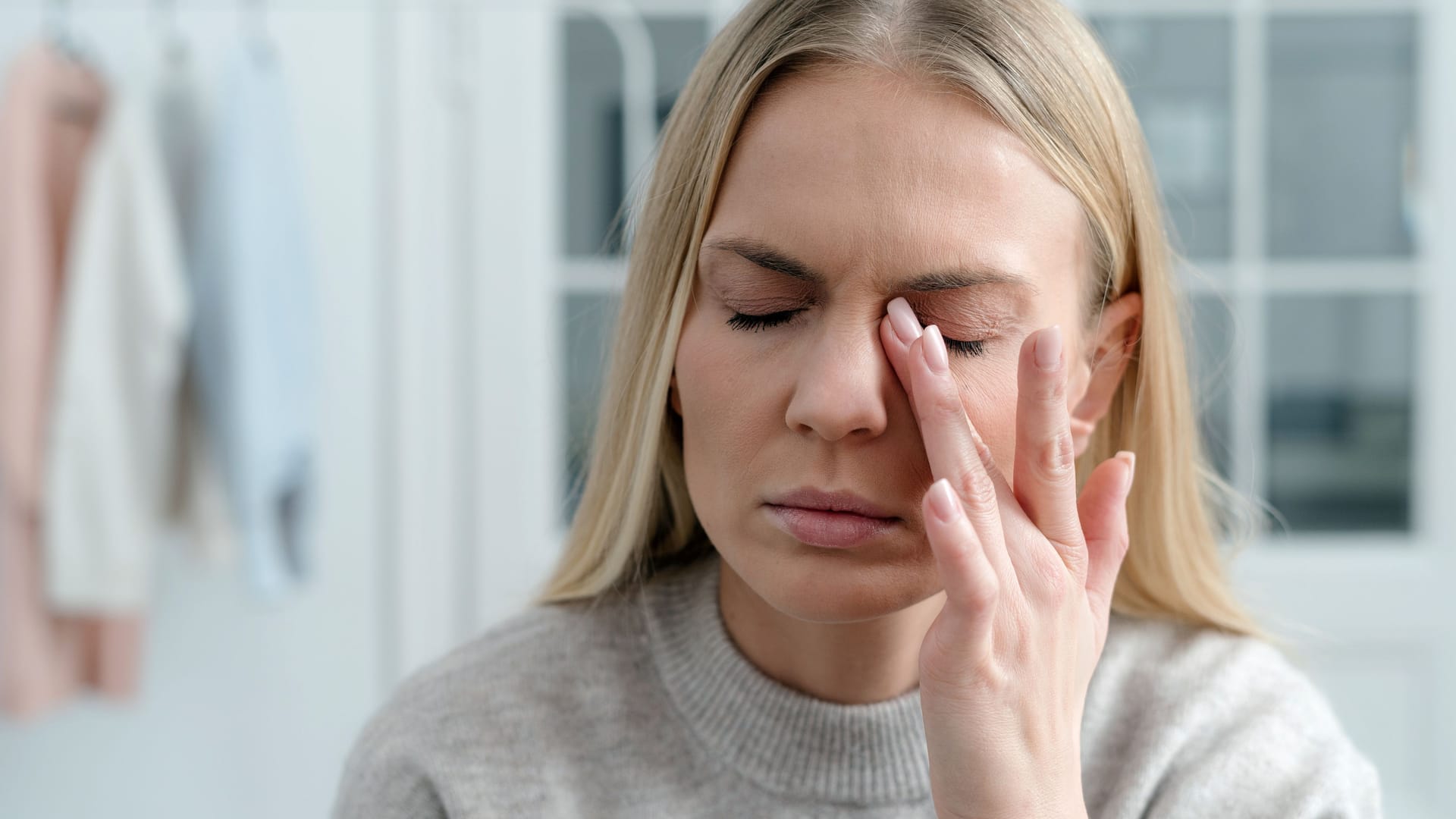 Eine Frau fasst sich ans Auge: Wer psychisch belastet ist und immer wieder tränende Augen hat, fragt sich möglicherweise, ob ein Zusammenhang bestehen kann.