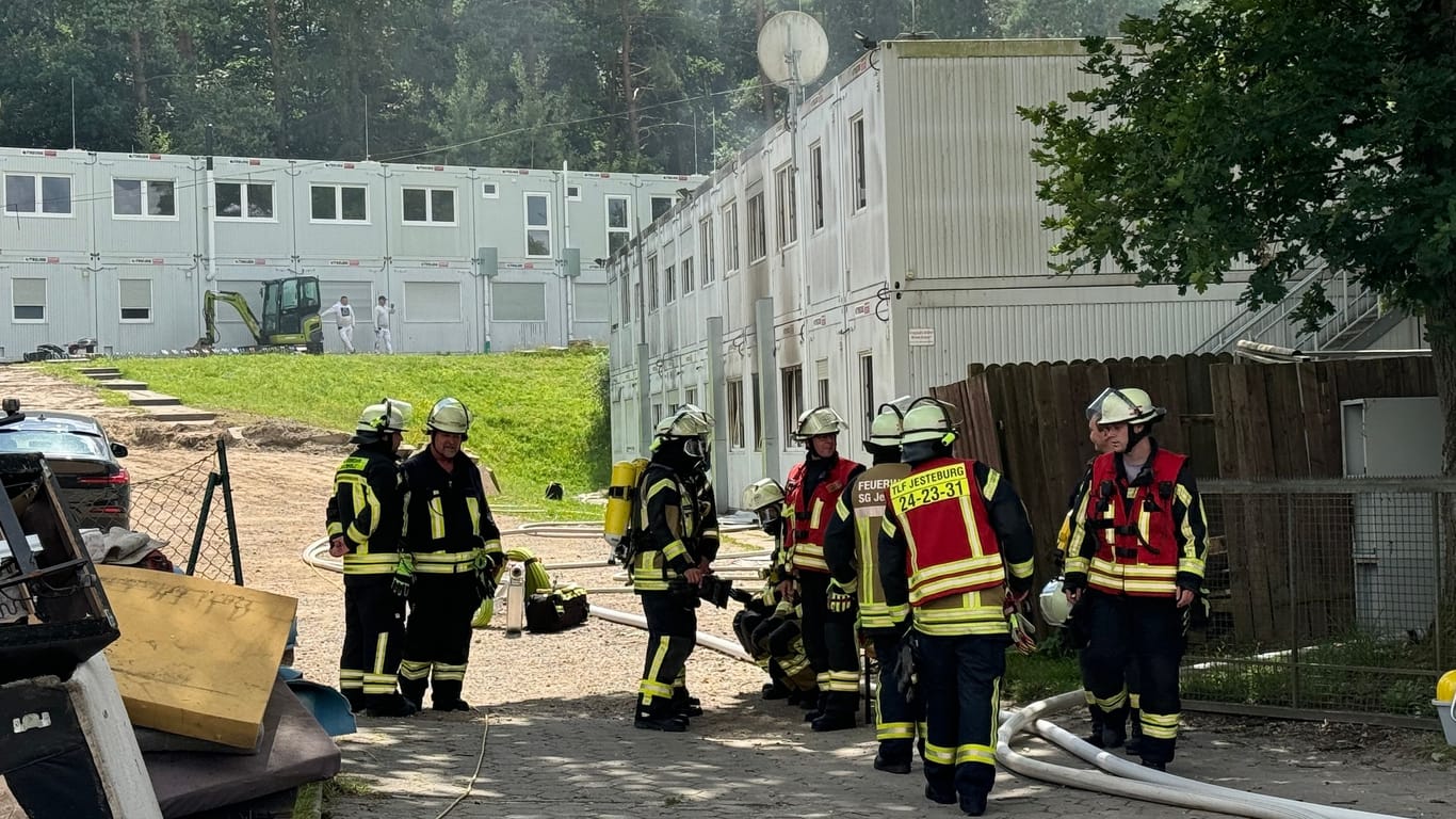 Feuerwehrleute stehen vor der Unterkunft: Der Komplex muss nach dem Brand offenbar abgerissen werden.