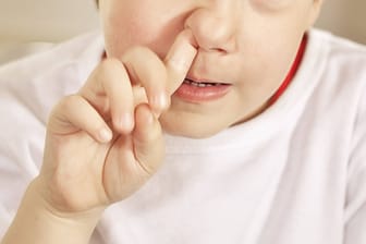 Ein Junge bohrt in der Nase (Archivbild): Weil ein Schüler im Bus gepopelt und randaliert haben soll, fesselte eine Busfahrerin das Kind.