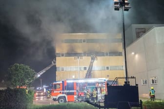 Feuerwehrleute löschen den Brand in einer Halle der durch ihren Zwieback bekannten Firma Brandt.