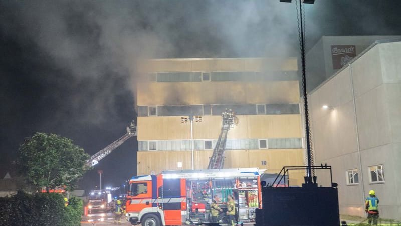 Feuerwehrleute löschen den Brand in einer Halle der durch ihren Zwieback bekannten Firma Brandt.