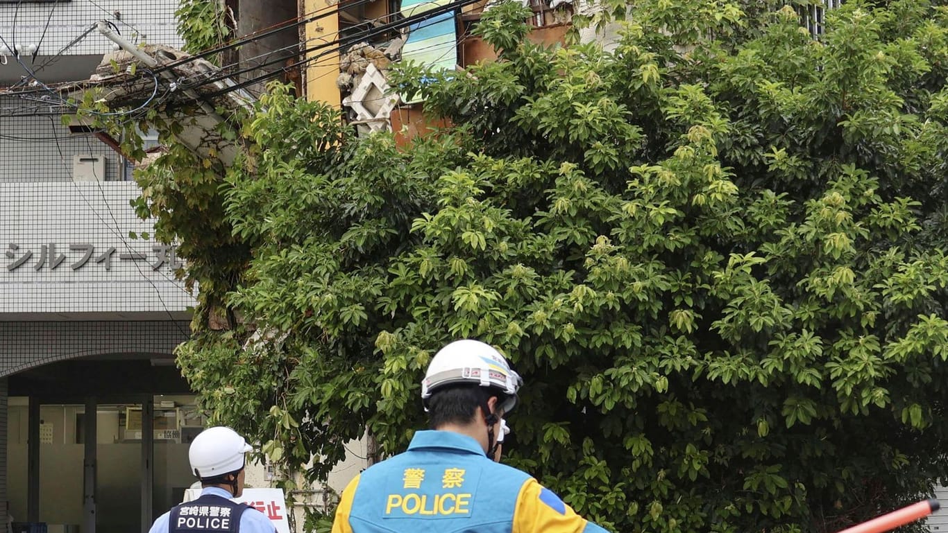 Polizisten stehen vor einem beschädigten Gebäude nach einem Erdbeben in Miyazaki.