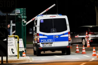 Ein Mannschaftswagen der Polizei fährt auf das militärische Gelände, links der Hinweis auf Security Alert State C.