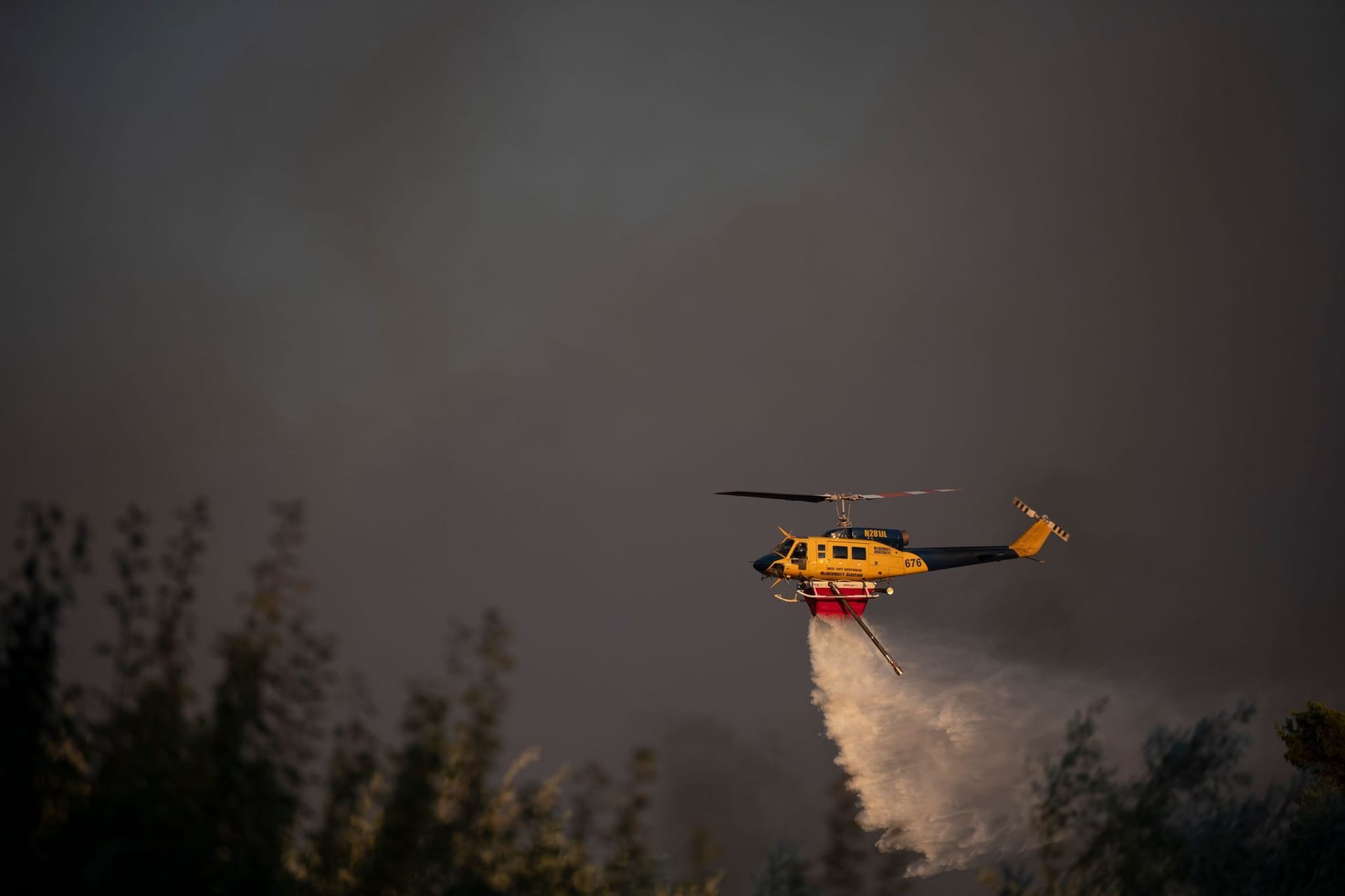 Ein Hubschrauber wirft während eines Waldbrandes in der Nähe des Dorfes Varnava Wasser ab.