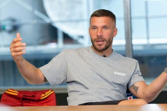 Der Fußballprofi Lukas Podolski sitzt bei einem Interview in einem Besprechungsraum: Am 10. Oktober soll sein Abschiedsspiel in Köln stattfinden.