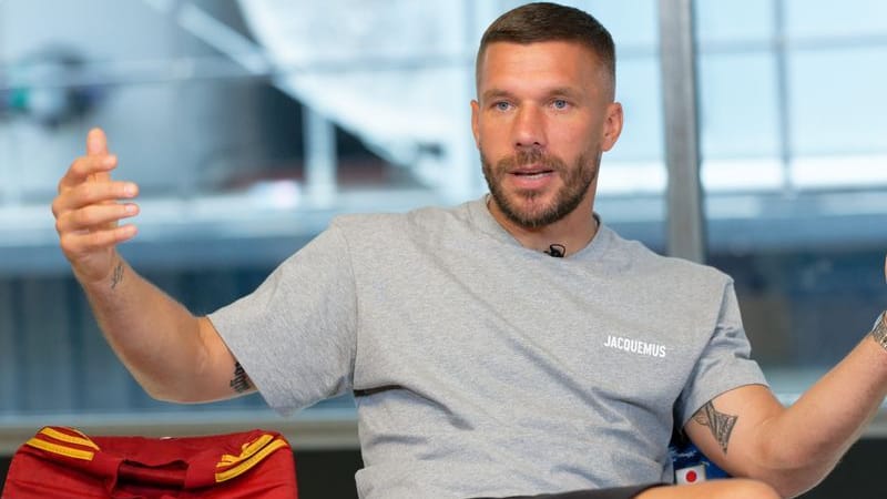 Der Fußballprofi Lukas Podolski sitzt bei einem Interview in einem Besprechungsraum: Am 10. Oktober soll sein Abschiedsspiel in Köln stattfinden.