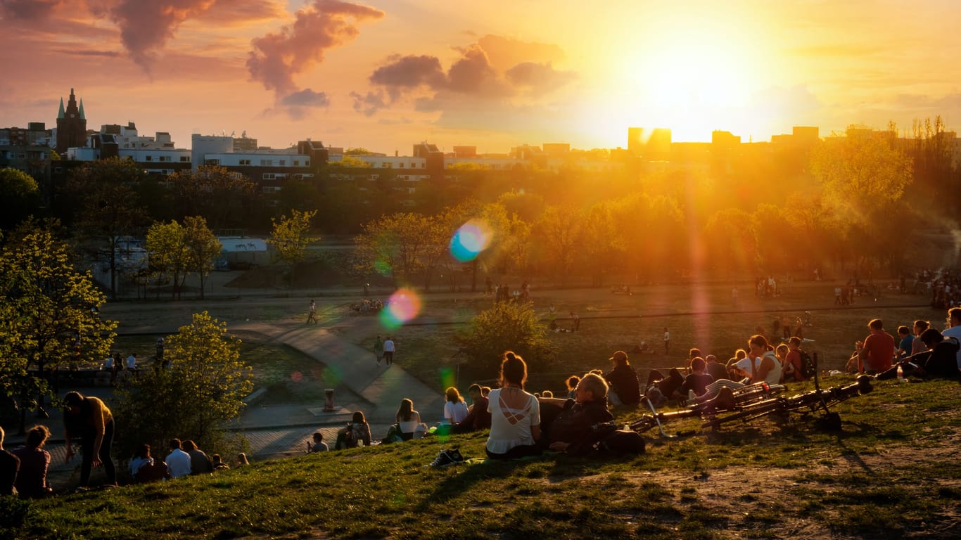 People enjoying view on sunset sky over skyline from public park (Mauerpark) on summer day in Berlin